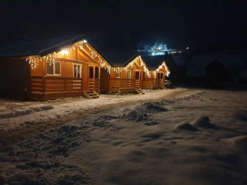 una fila di rifugi in legno nella neve di notte di Cabane La Petrică a Borşa