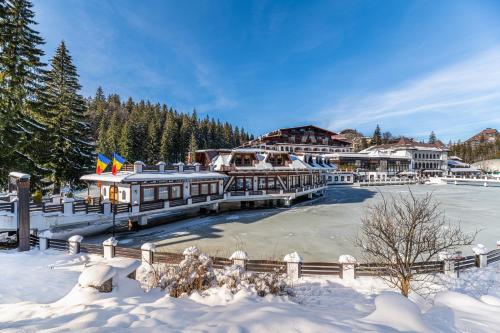 a resort in the snow with a frozen lake at Aurelius Imparatul Romanilor Hotel & SPA in Poiana Brasov