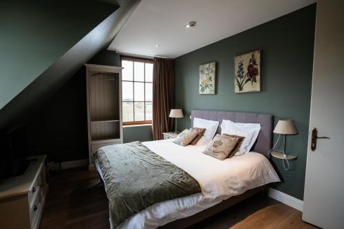 a bedroom with green walls and a bed with pillows at Dartmoor Cottage in Merris