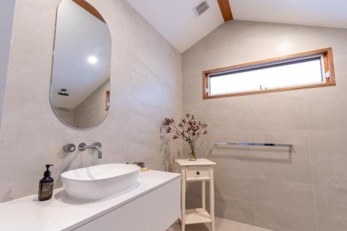 W białej łazience znajduje się umywalka i lustro. w obiekcie Currajong Retreat w mieście Burragate