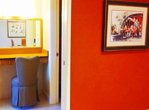 a room with a red wall with a chair and a mirror at Howard Johnson by Wyndham Anaheim Hotel & Water Playground in Anaheim