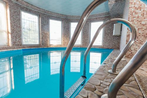 une piscine intérieure avec un escalier roulant dans un bâtiment avec fenêtres dans l'établissement Hotel Citadel, à Skhidnitsa