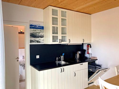 a kitchen with white cabinets and a sink at Zum Seglerhafen – Ferienappartement in Kressbronn am Bodensee