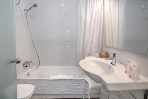 a white bathroom with a sink and a bath tub at Hotel La Cala Finestrat in Cala de Finestrat