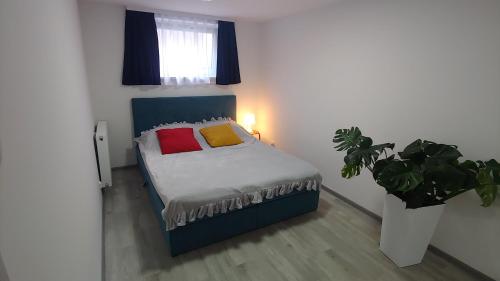 1 dormitorio con 1 cama con 2 almohadas y planta en Apartament Arkadia Storczyk, en Augustów