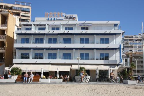 um hotel na praia com pessoas sentadas em frente a ele em Hotel La Cala Finestrat em Cala de Finestrat