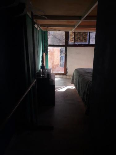 um quarto escuro com uma cama e uma janela em Suit compartida con amenidades em Cidade do México
