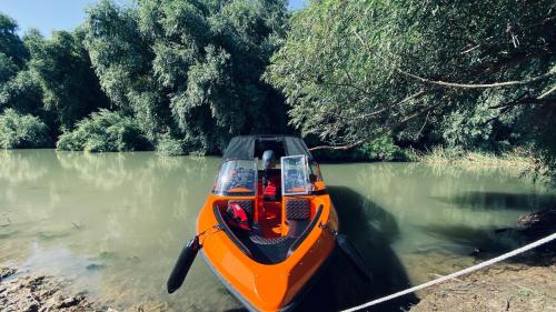 an orange boat in the water on a river at Manu B&B in Murighiol