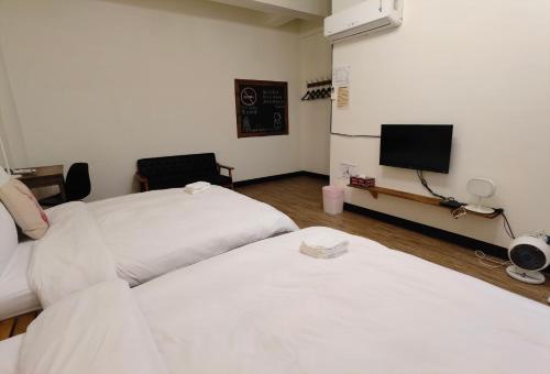 a room with two beds and a tv in it at OC Hostel in Tainan