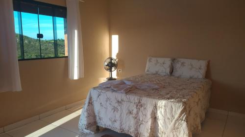 a bedroom with a bed with a lamp and a window at Pousada Mirante Das Serras Ibicoara-BA in Ibicoara