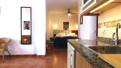 a kitchen with a sink and a living room with a bed at Apartamentos Nerjaluna in Nerja
