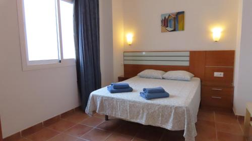 a bedroom with a bed with two blue towels on it at Apartamentos Nerjaluna in Nerja