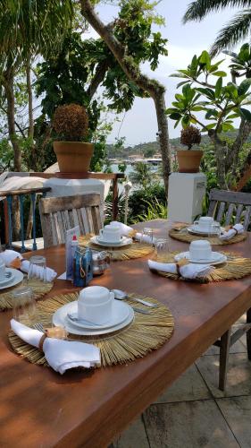 einem Holztisch mit Tellern und Servietten darauf in der Unterkunft Pousada Casa Búzios in Búzios