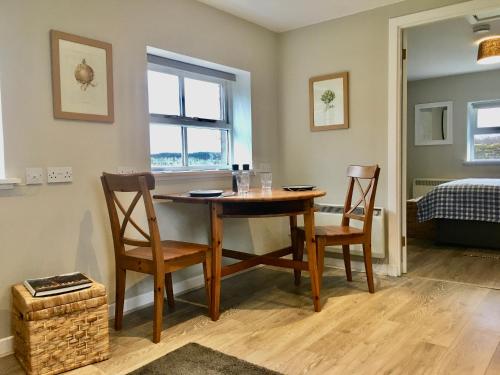 uma sala de jantar com uma mesa e duas cadeiras em Woodside Cottage Self Catering em Kinbuck