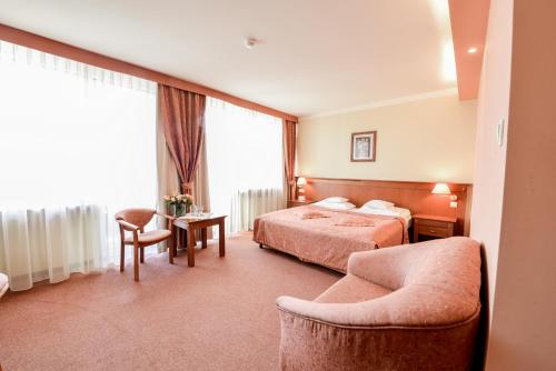 a hotel room with two beds and a chair at SPA Hotel Jawor in Jaworze