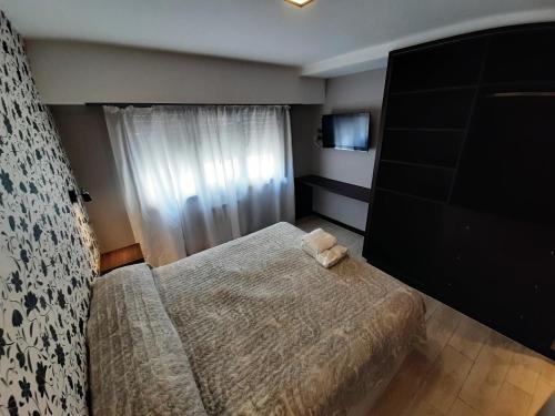 Dormitorio pequeño con cama y TV en Hotel Castellon en Mar del Plata