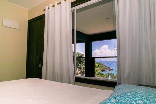 a bedroom with a window with a view of the ocean at Pousada La Dolce Vita in Búzios