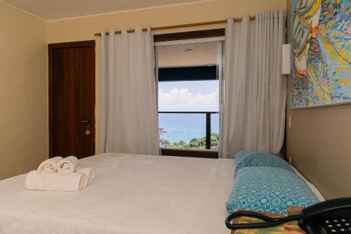 a bedroom with a bed with towels and a window at Pousada La Dolce Vita in Búzios