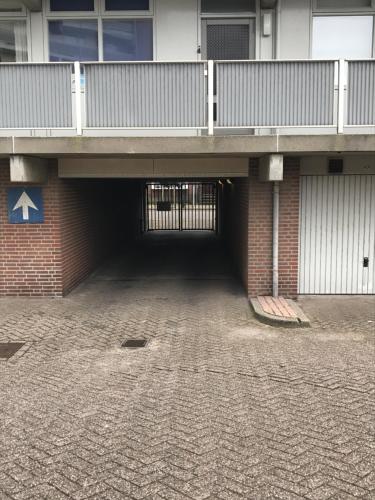a parking lot under a building with a balcony at Huisje 16 in Noordwijk aan Zee
