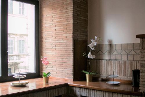 a room with a brick wall and a counter with potted plants at Morgan Suite Roma in Rome
