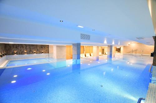 a large swimming pool in a building with blue lighting at Mirage Resort & Spa in Vişeu de Sus