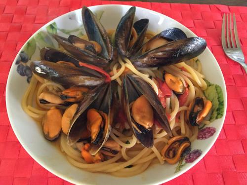 a bowl of pasta with mussels on a table at PINOKKIO B&B Restaurant in Jimbaran