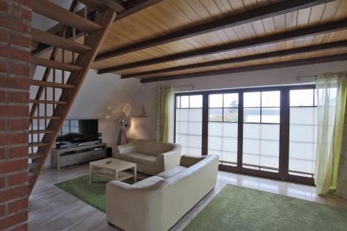 a living room with a couch and a tv and windows at Hotel & Restaurant Am Wasser in Breege