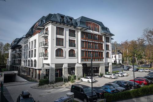 a large white building with cars parked in a parking lot at Nosalowy Park Hotel & Spa in Zakopane