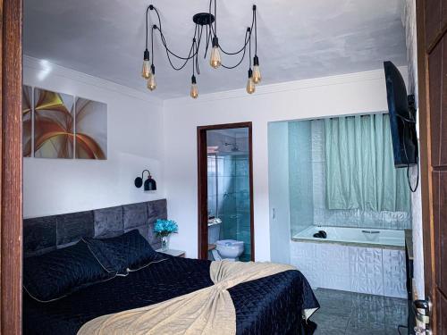 a bedroom with a bed and a bathroom with a tub at Recanto Bella Fonte in Monte Verde