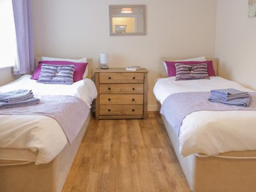 a bedroom with two twin beds and a dresser at Stable Cottage Llandudno in Llandudno
