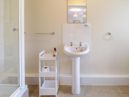 a white bathroom with a sink and a shower at Stable Cottage Llandudno in Llandudno