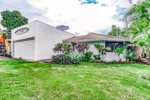 a white house with a garage in a yard at Kona Paradise in Kailua-Kona