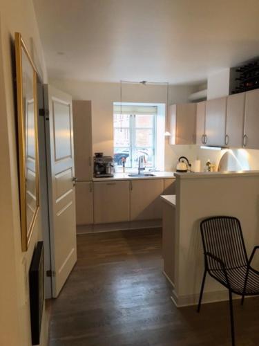 uma cozinha com uma cadeira, uma mesa e um lavatório em Stemningsfuld lejlighed - 3 minutters gang fra H.C. Andersens Hus em Odense