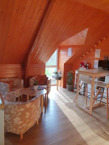 Elle comprend un salon doté de plafonds en bois et d'une table. dans l'établissement LES CHEVAUX DE L'HIPPOCAMPE, à Mont-Dol