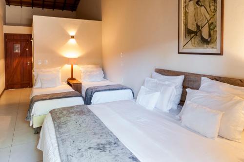 a hotel room with three beds with white sheets at Pousada da Cyssa in Búzios