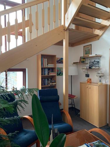a living room with a staircase and a blue chair at Penzion Na Solné stezce in Kašperské Hory