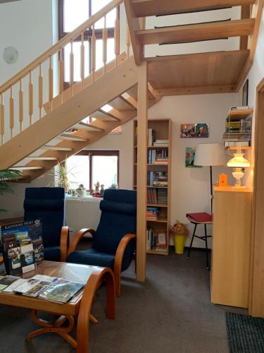 a living room with two chairs and a staircase at Penzion Na Solné stezce in Kašperské Hory