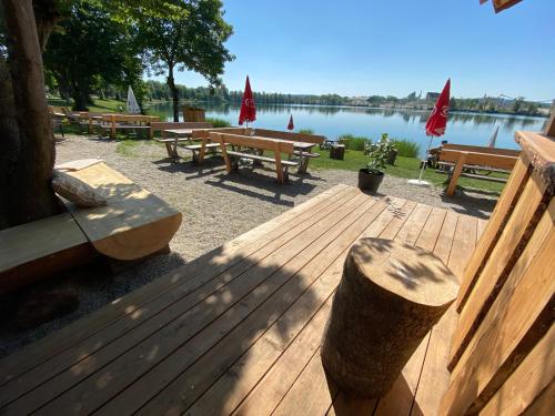 a wooden deck with benches and a lake at Seehaus Mamming - Hotel - Schlaffässer - Biergarten - Camping in Mamming