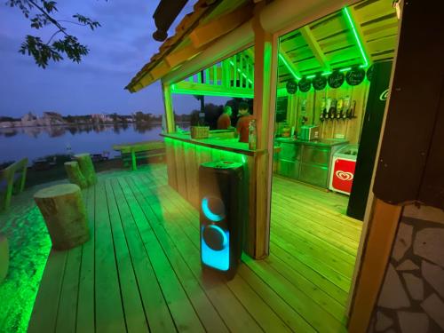 a bar on a deck with green lights at Seehaus Mamming - Hotel - Schlaffässer - Biergarten - Camping in Mamming