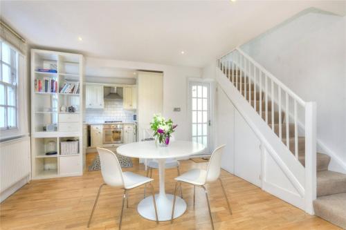 a white dining room with a white table and chairs at Charming Cottage & Garden - central Brighton! in Brighton & Hove