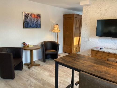 a living room with a table and chairs and a television at Hotel Wintersmühle in Bielefeld