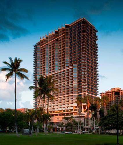 a tall building with palm trees in a park at Ka Laʻi Waikiki Beach, LXR Hotels & Resorts in Honolulu