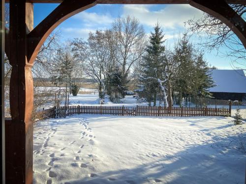 a fence in the snow with footprints in it at Sosnowy domek w rezerwacie nad Narwią in Bokiny