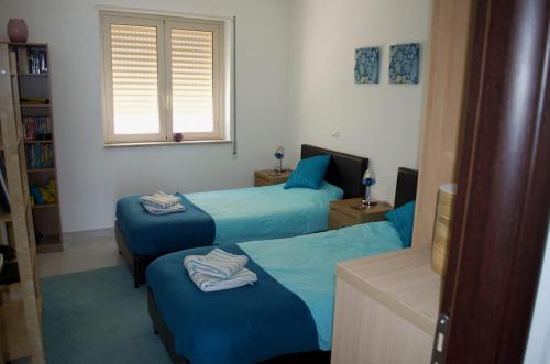 1 Schlafzimmer mit 2 Betten mit blauer Bettwäsche und einem Fenster in der Unterkunft Pizzo Heights in Pizzo