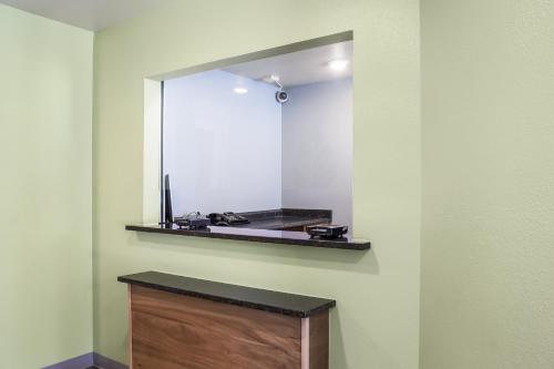 a bathroom with a mirror and a wooden vanity at WoodSpring Suites McKinney in McKinney