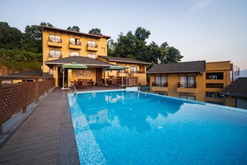 a large blue swimming pool in front of a building at Bar Peepal Resort in Pokhara