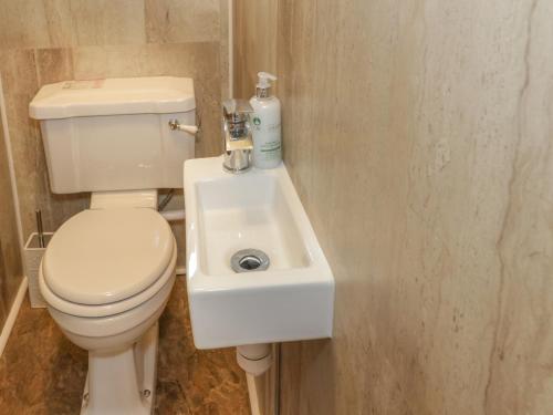 a bathroom with a white toilet and a sink at Hardy Cottage in Benllech
