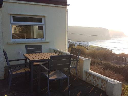 a wooden table and chairs on the balcony of a house at White Ocean in Mawgan Porth