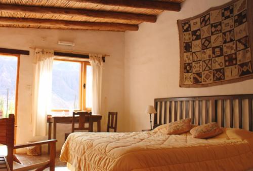 Schlafzimmer mit einem Bett, einem Schreibtisch und einem Fenster in der Unterkunft Huaira Huasi in Purmamarca