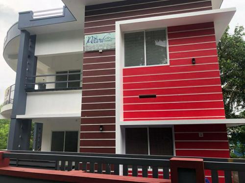 a red and white building with a balcony at Pearl Inn in Kottakkal